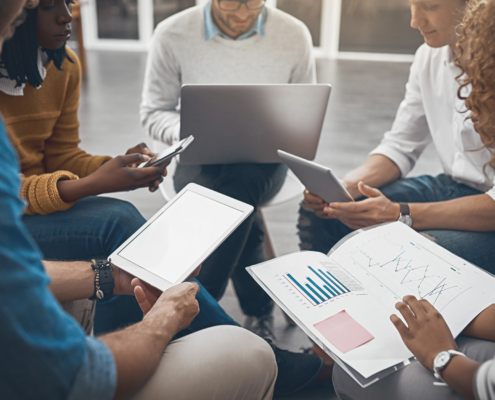 Side view of a group of people sitting in a circle looking at financial documents