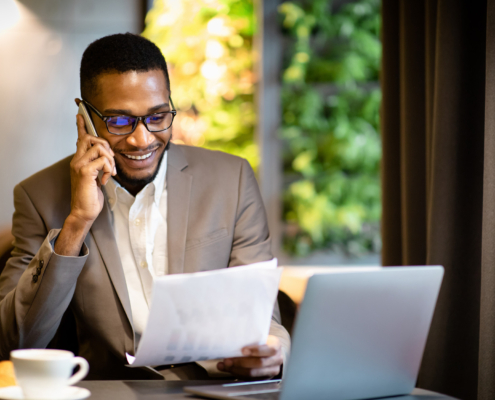 Front view of smiling young accountant looking over documents while working in a cafe